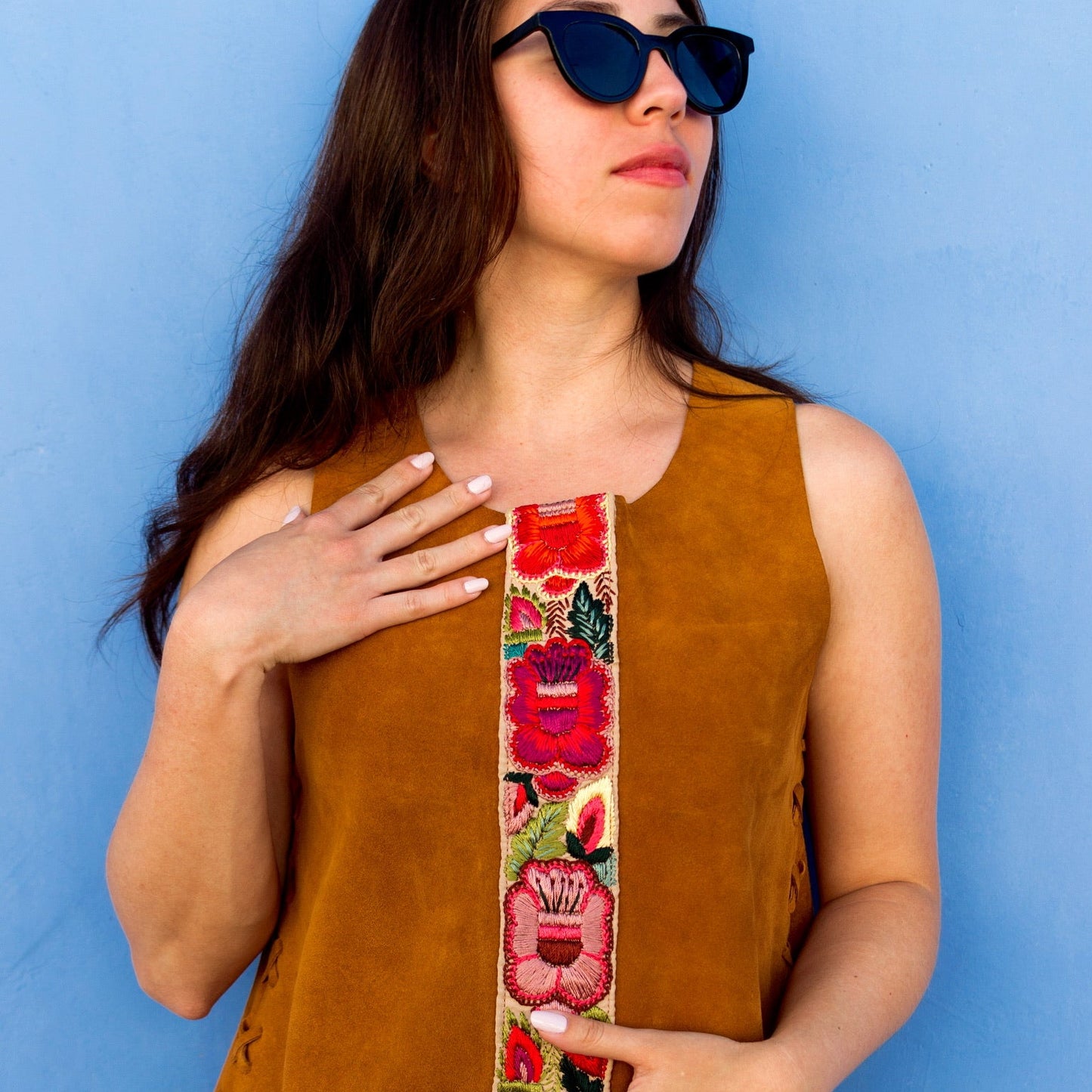 Woman holding a colorful belt with floral design against a blue background
