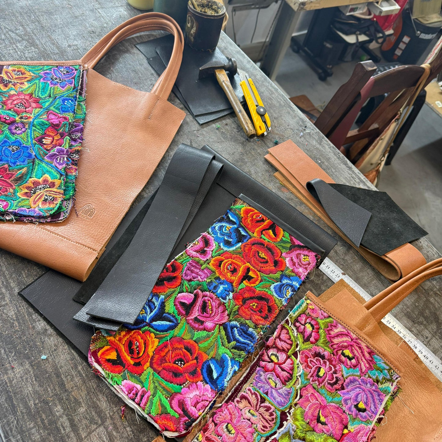 Colorful floral-patterned leather goods on a table with sewing equipment in the background.