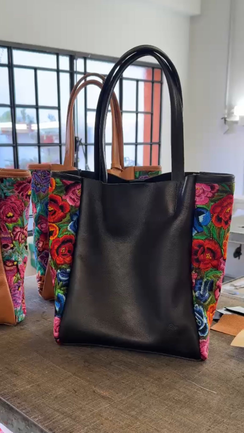 Black tote bag with colorful floral pattern on a wooden surface