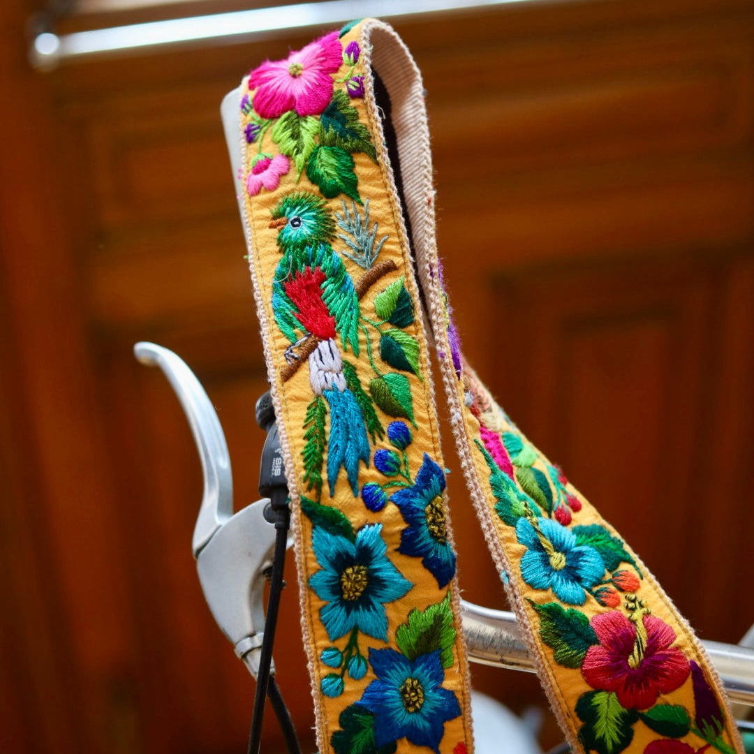 Colorful embroidered guitar strap with floral patterns on a wooden background