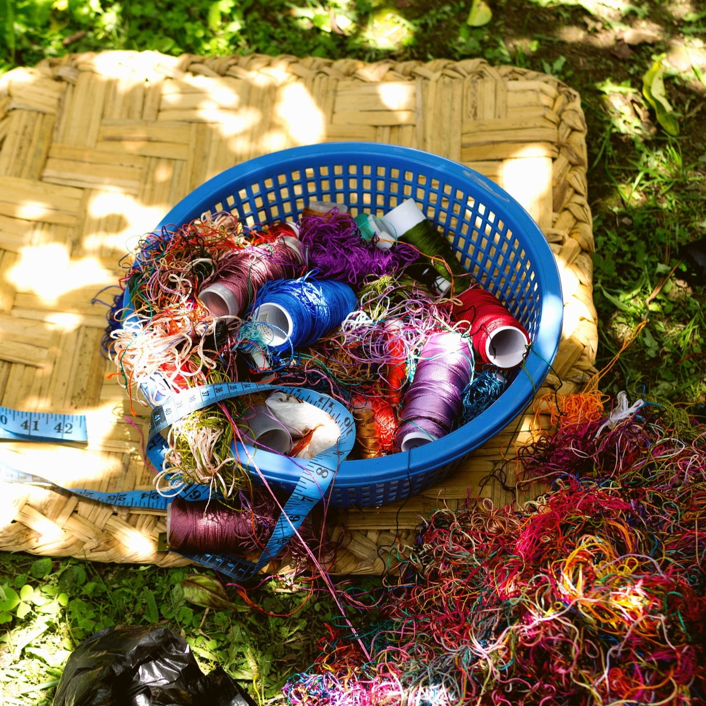 Basket with colorful yarn and spools on a grassy surface