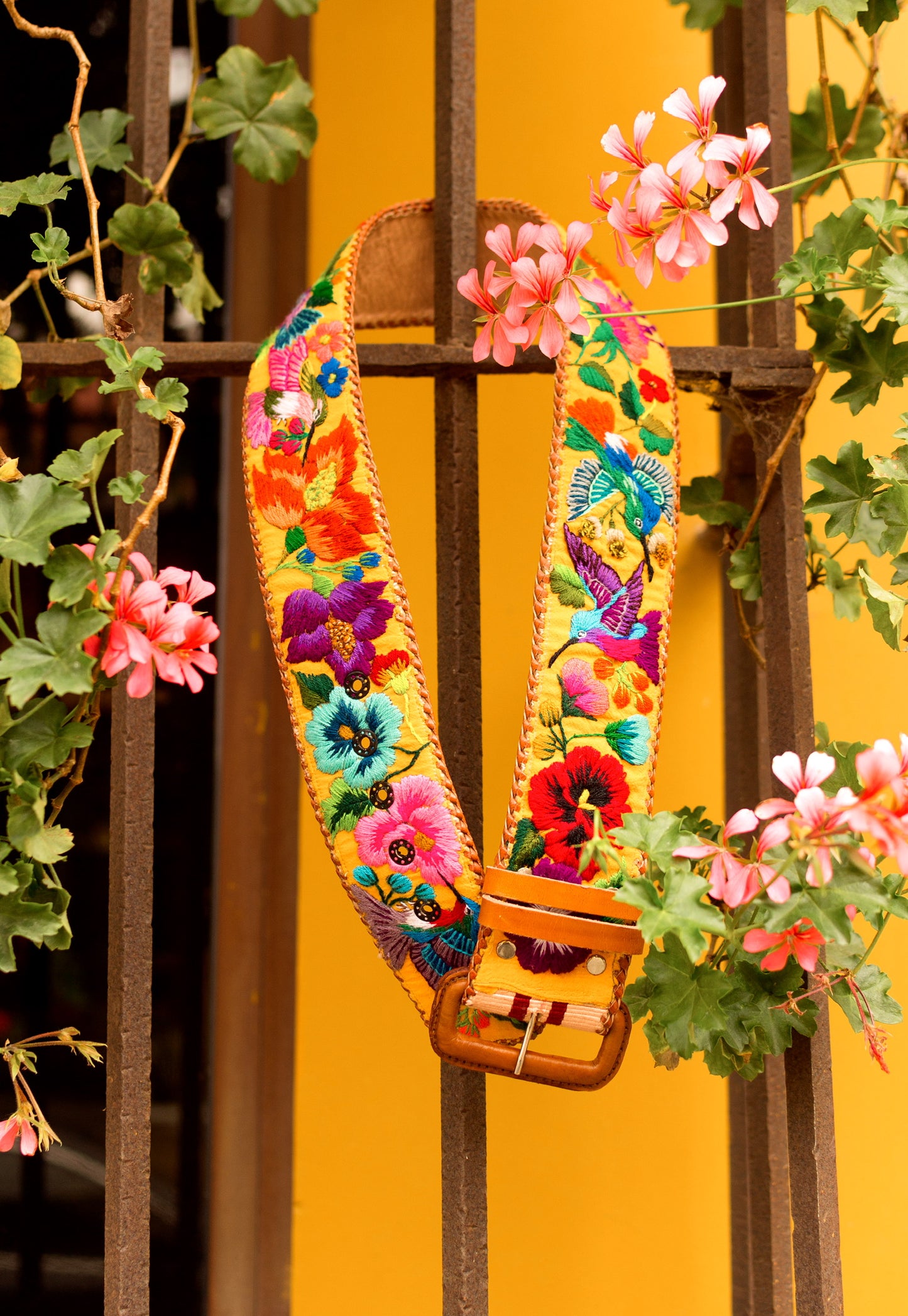 Colorful floral-patterned strap against a yellow wall with greenery