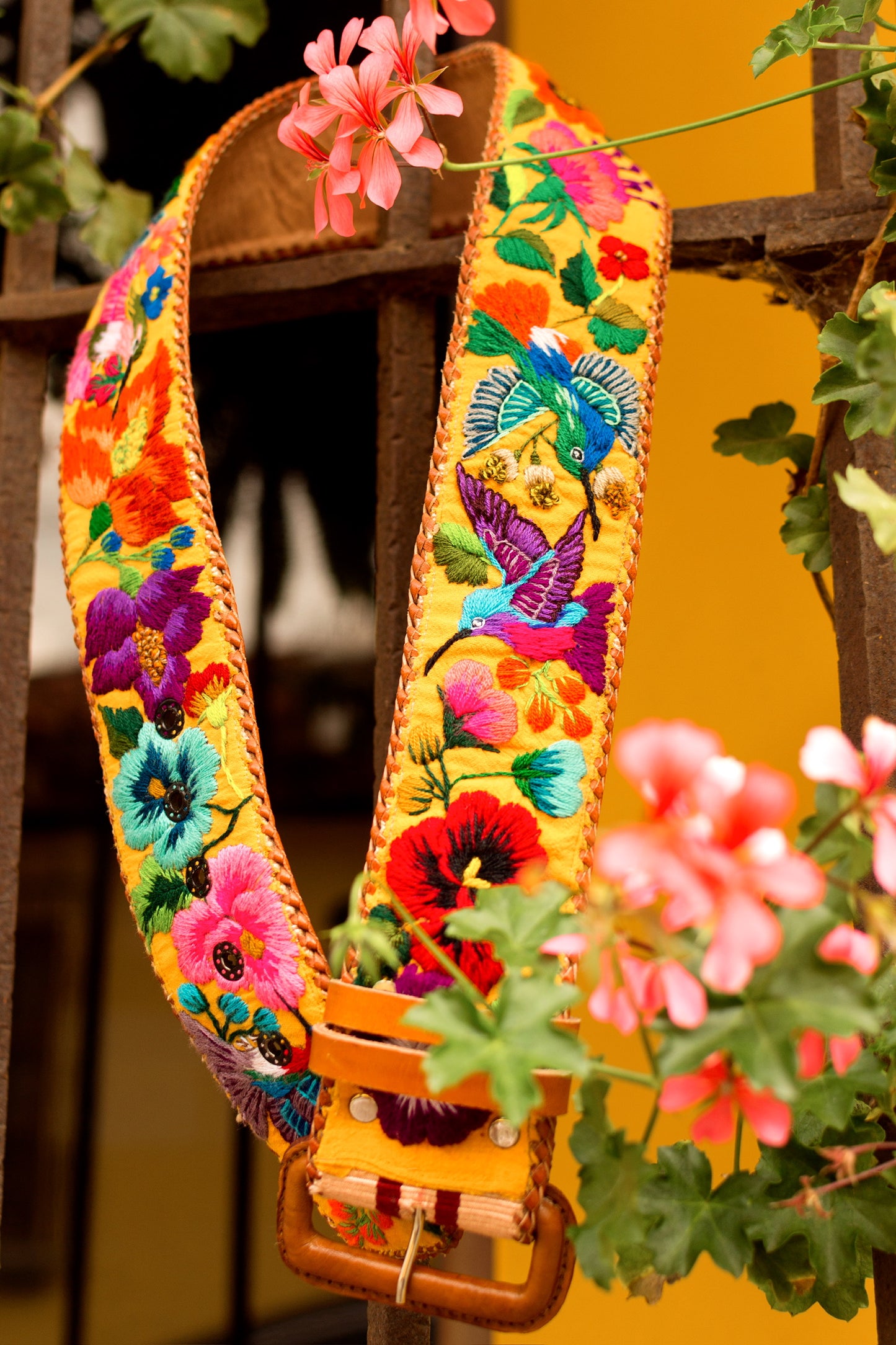 Colorful floral embroidery strap with wooden handle against a blurred natural background