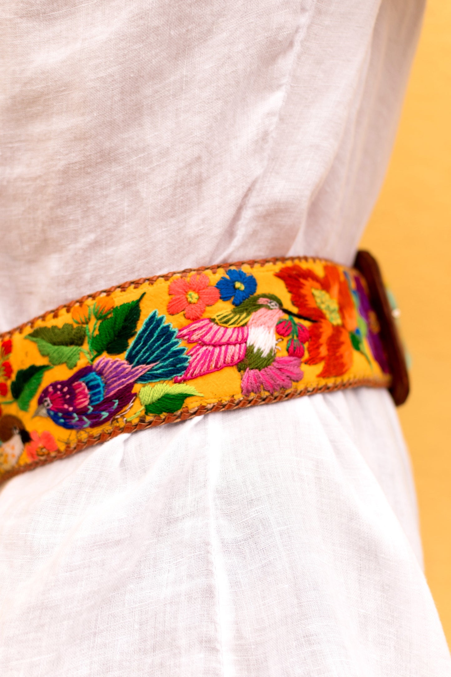 Colorful embroidered belt with floral and bird patterns on a plain background