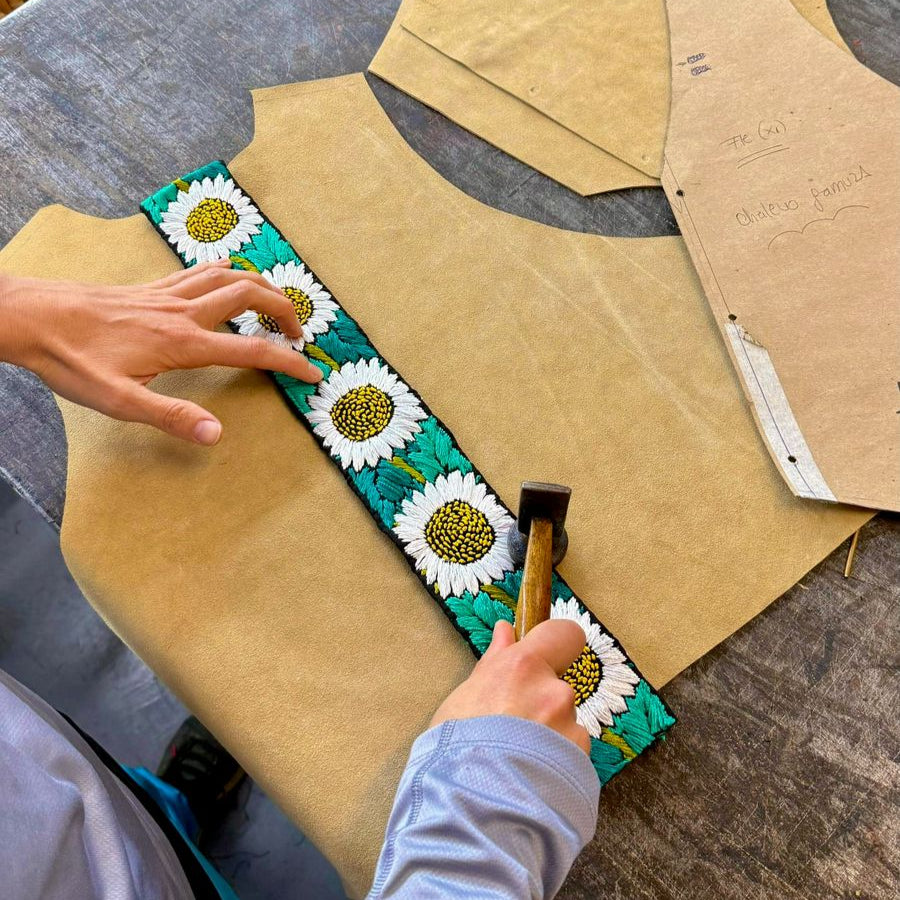 Person applying a floral pattern to cardboard with a hammer
