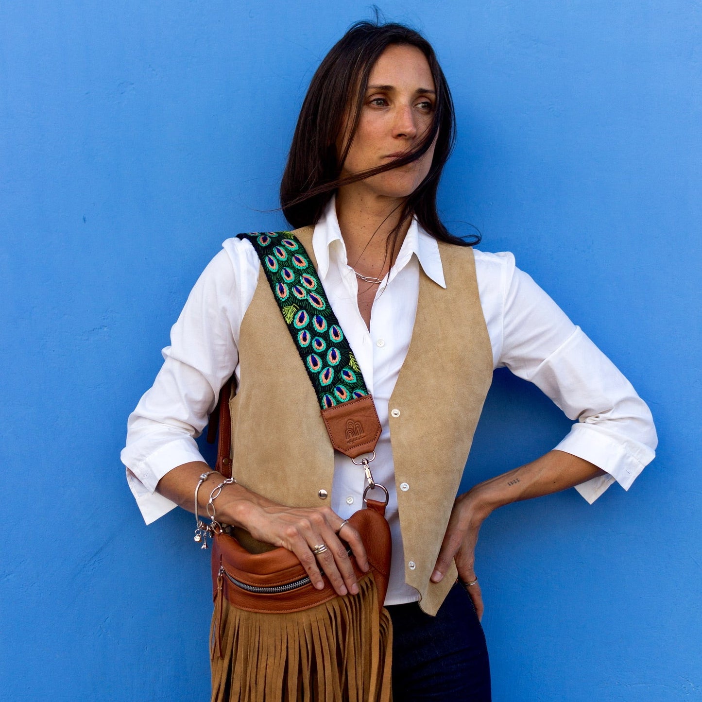 Woman holding a fringed leather bag against a blue background