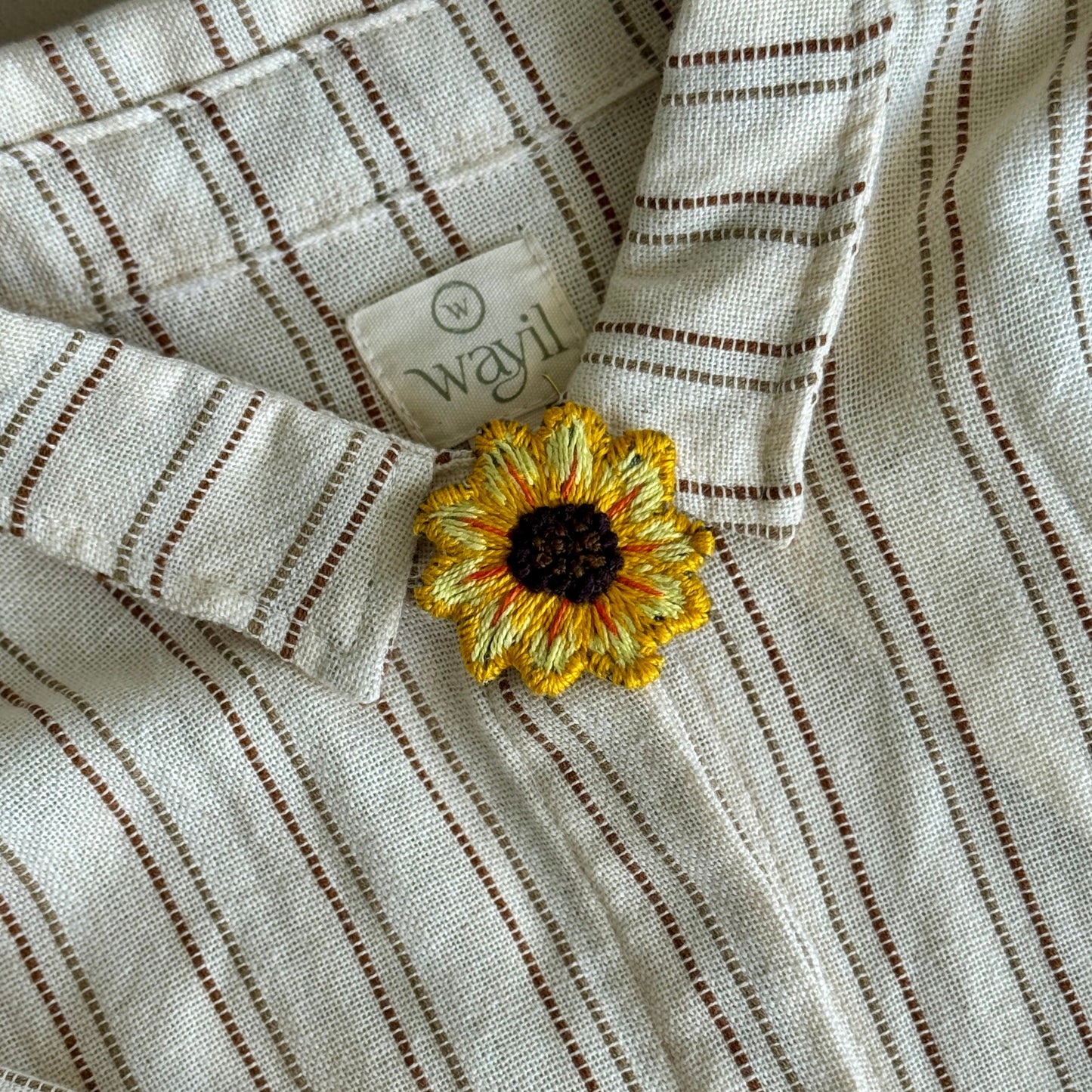 Striped fabric with a sunflower decoration and a visible brand label.