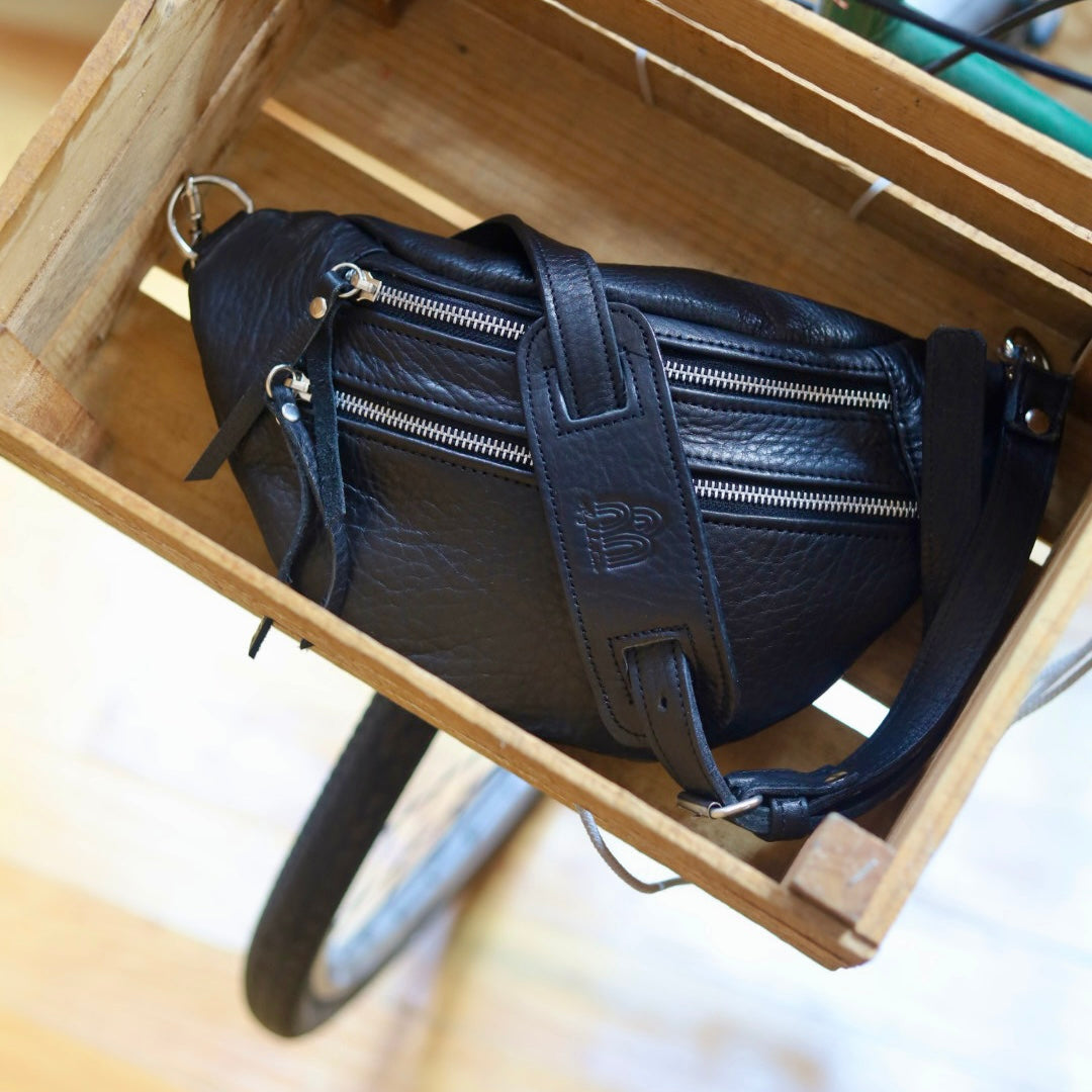 Black leather handbag inside a wooden box with a bicycle in the background