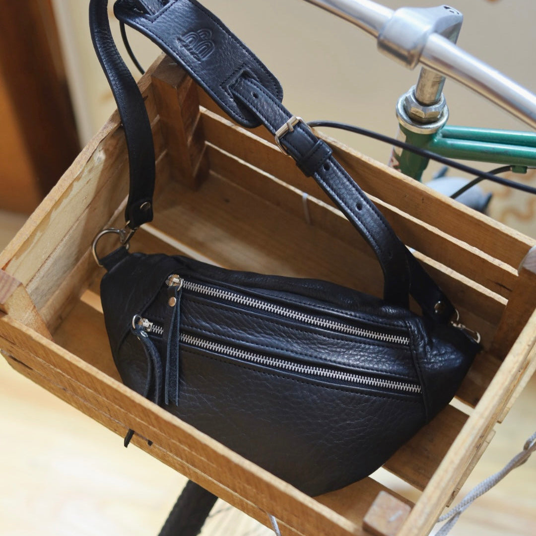 Black leather bag on a wooden stand with a bicycle in the background