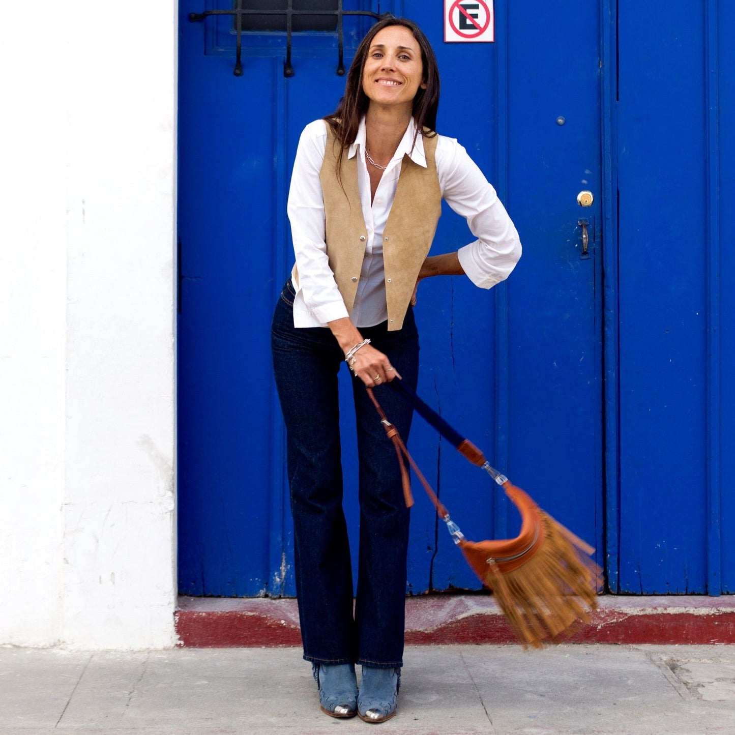 Woman holding a broom in front of a blue door