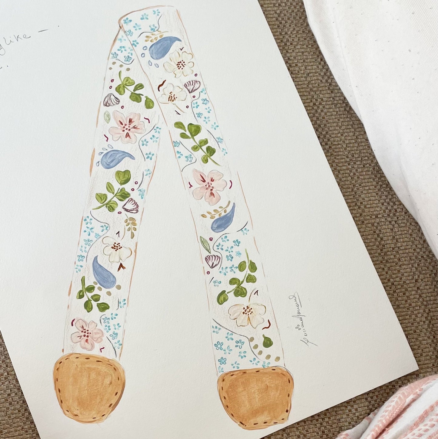 Decorative headband with floral and bird pattern on a white card, placed on a textured surface.