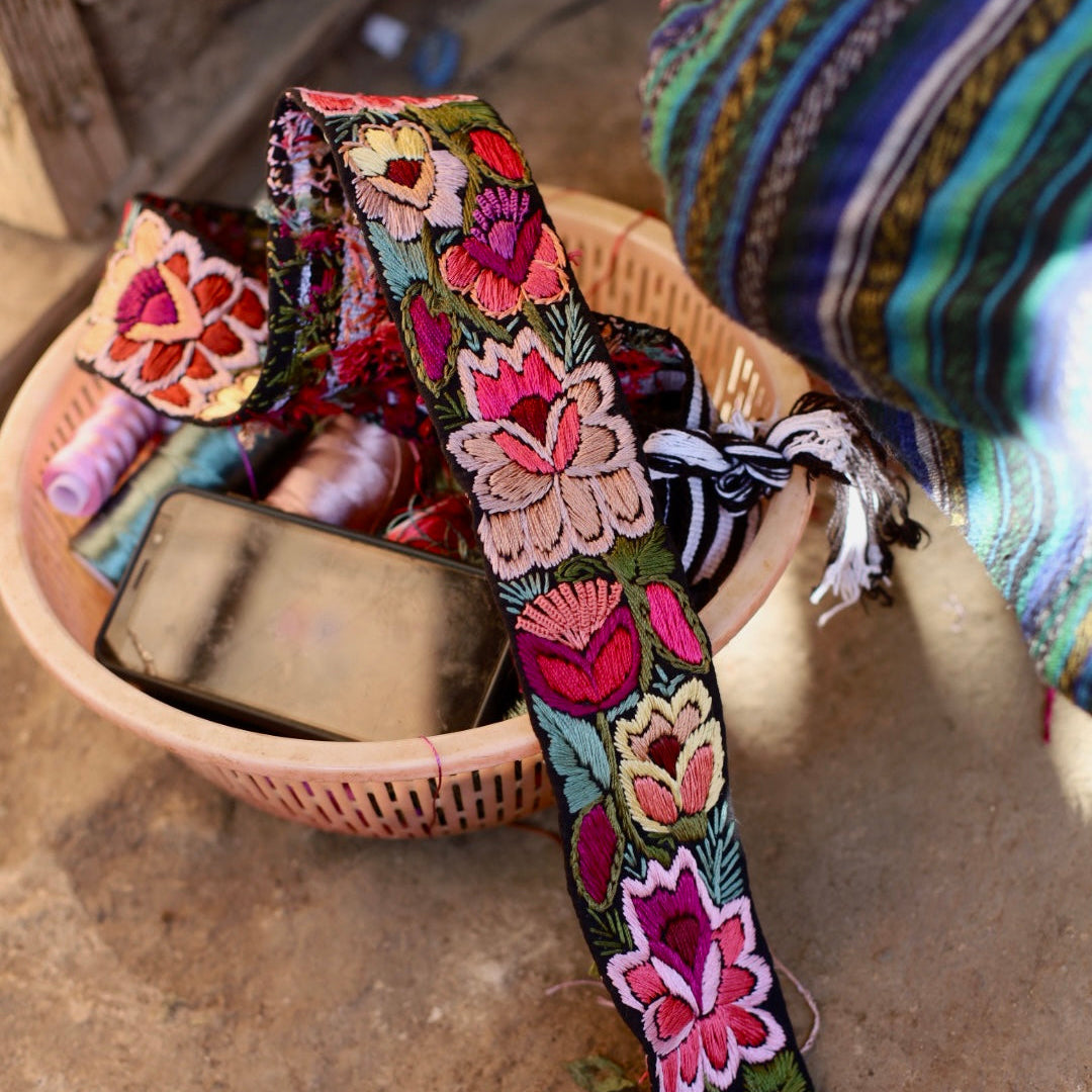 Colorful embroidered belt with floral patterns on a woven basket.