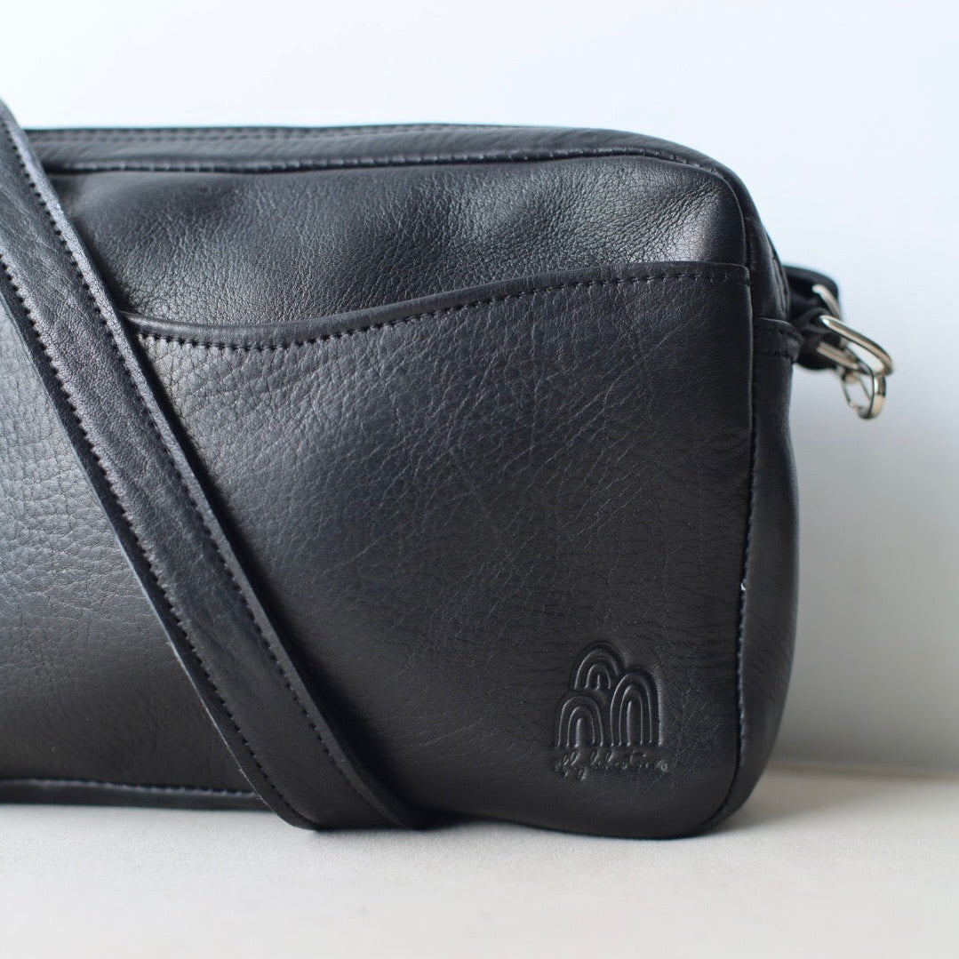 Black leather crossbody bag with a brand logo on a white background