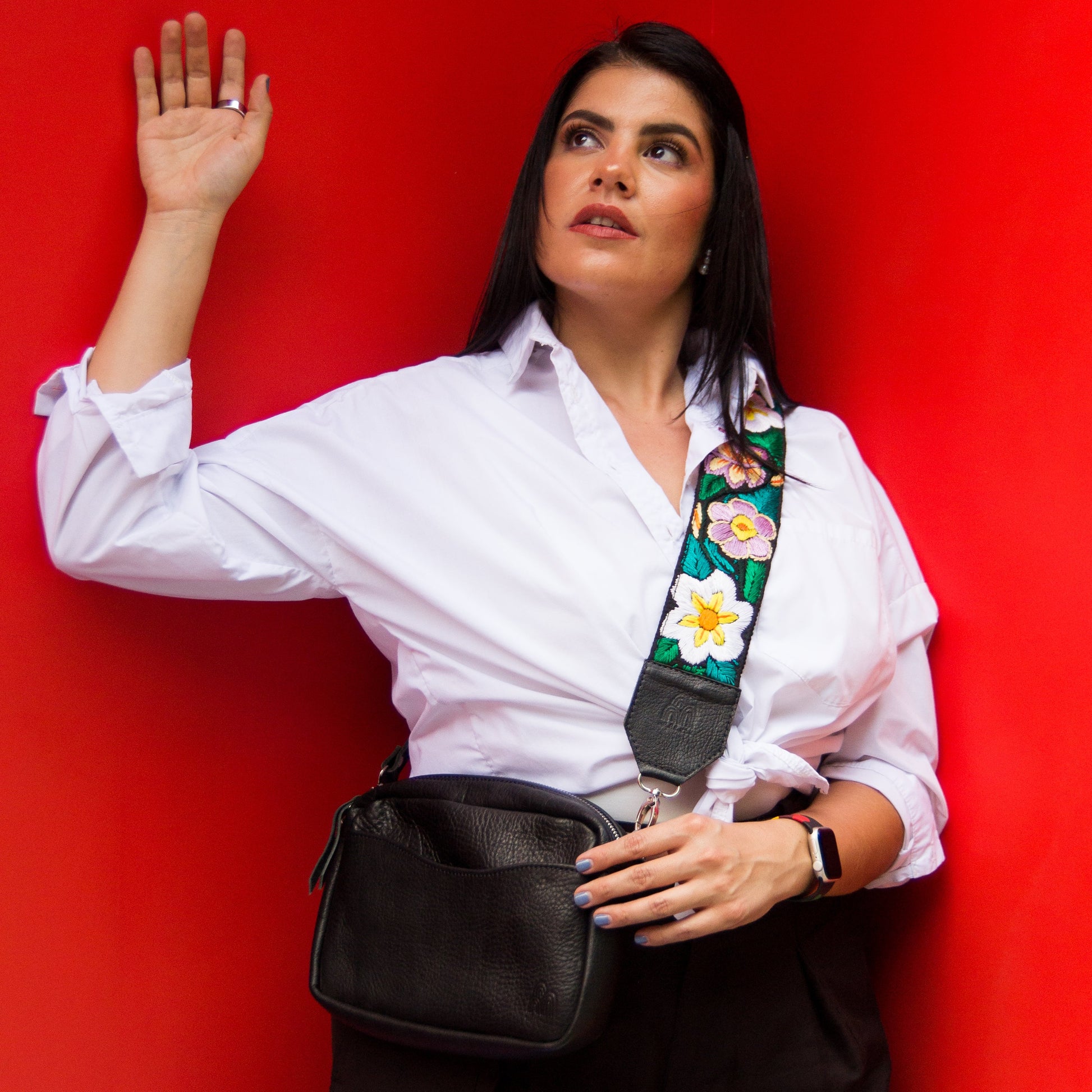 Woman wearing a white shirt with a floral strap against a red background