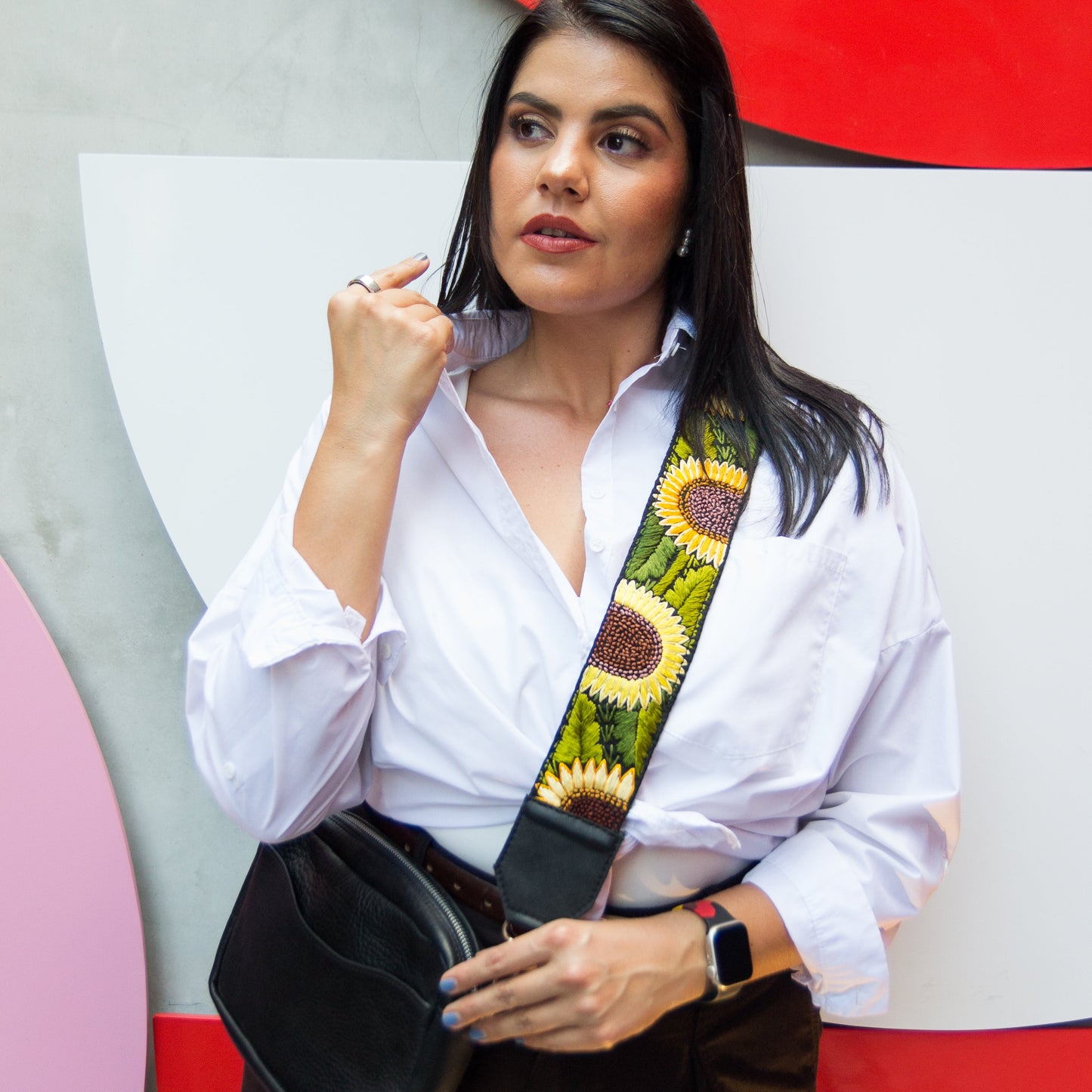 Woman wearing a white shirt with a sunflower-patterned belt against a colorful abstract background