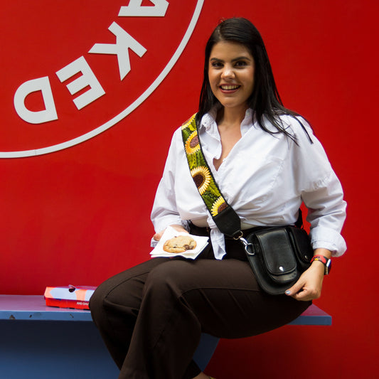 Woman sitting on a bench with a 'Baked' sign in the background