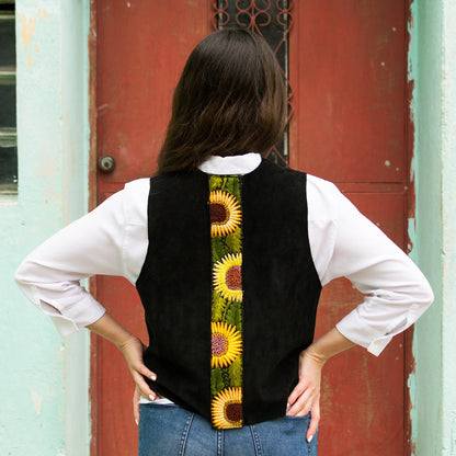Person wearing a black vest with sunflower pattern in front of a red door.