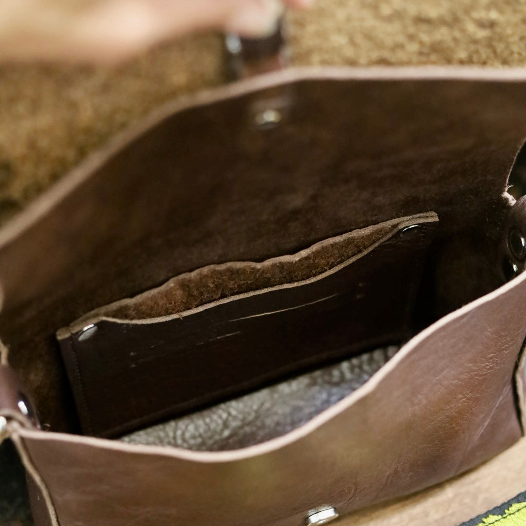 Close-up of a brown leather bag with a visible brand logo.