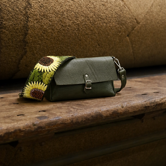 Green handbag with sunflower design strap on a wooden surface