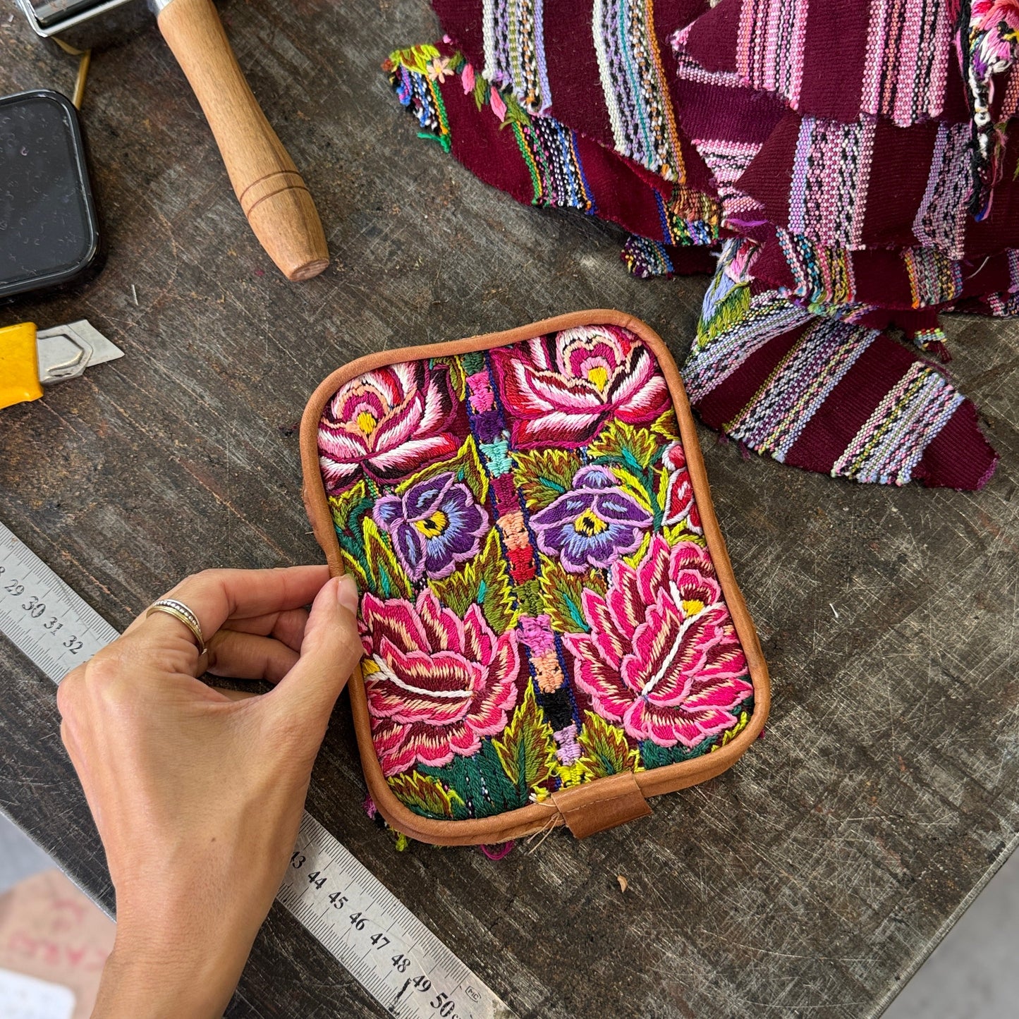 Handmade embroidered box with colorful floral patterns on a wooden surface.