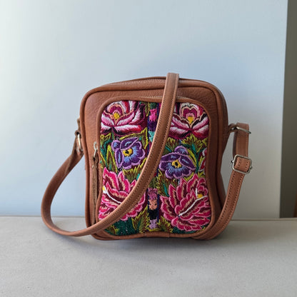 Floral embroidered crossbody bag on a light surface with a neutral background