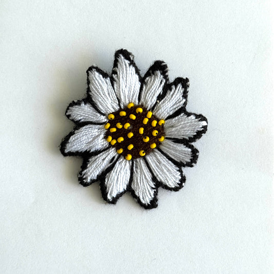 Embroidered daisy flower patch on a white background