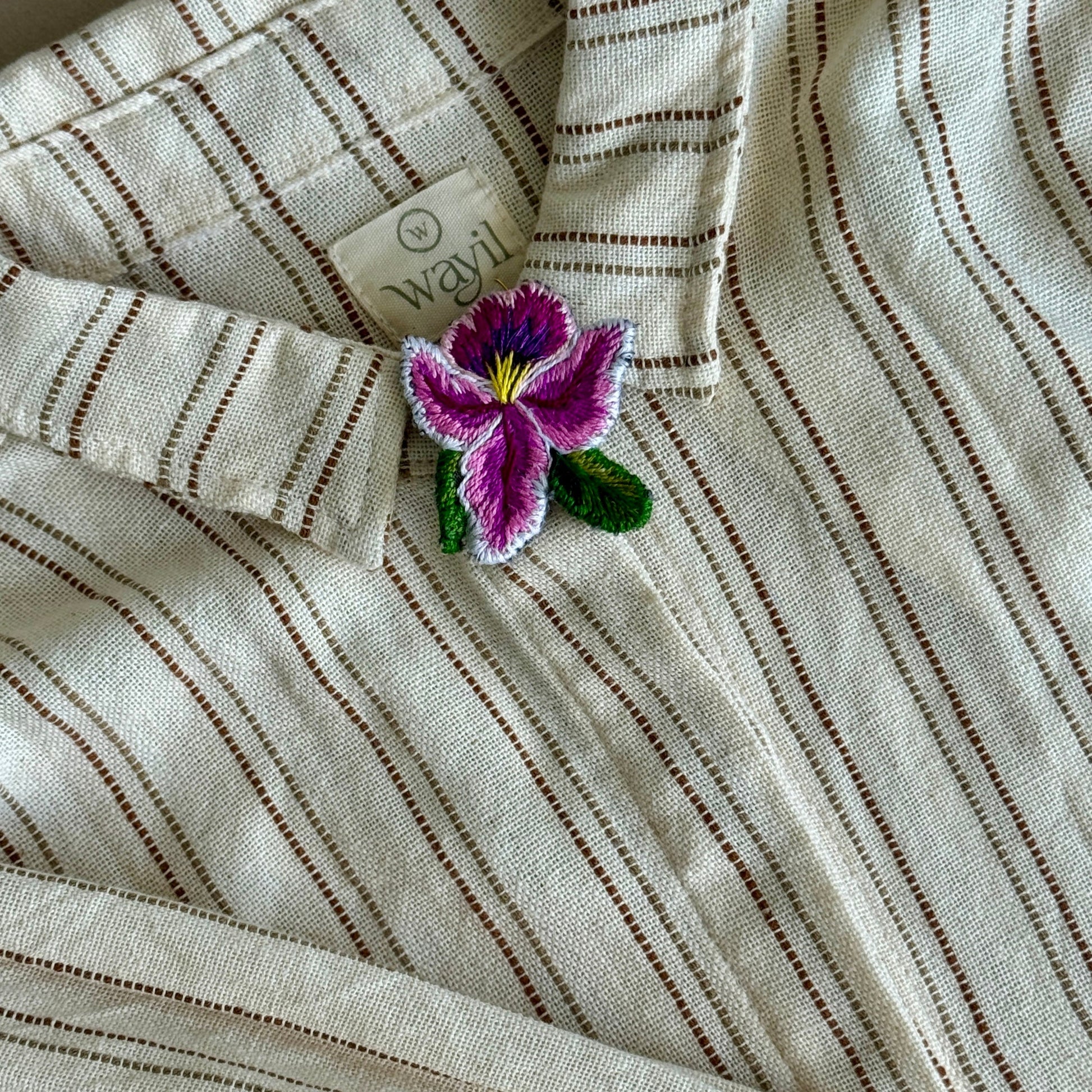 Striped fabric with a purple flower brooch on a neutral background