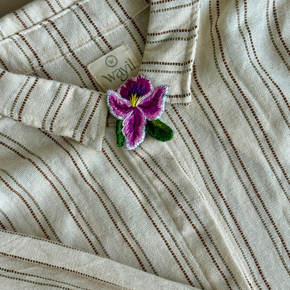 Striped fabric with a purple flower brooch on a neutral background