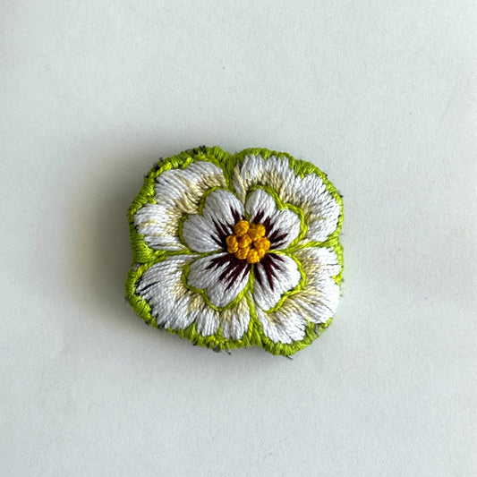 Embroidered flower brooch on a white background