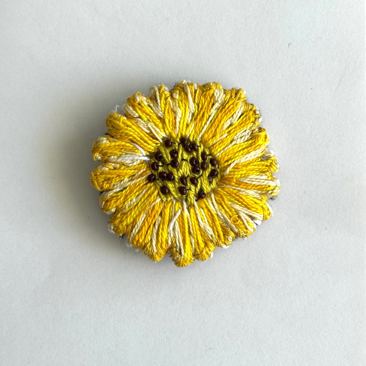Gold flower-shaped brooch on a light gray background