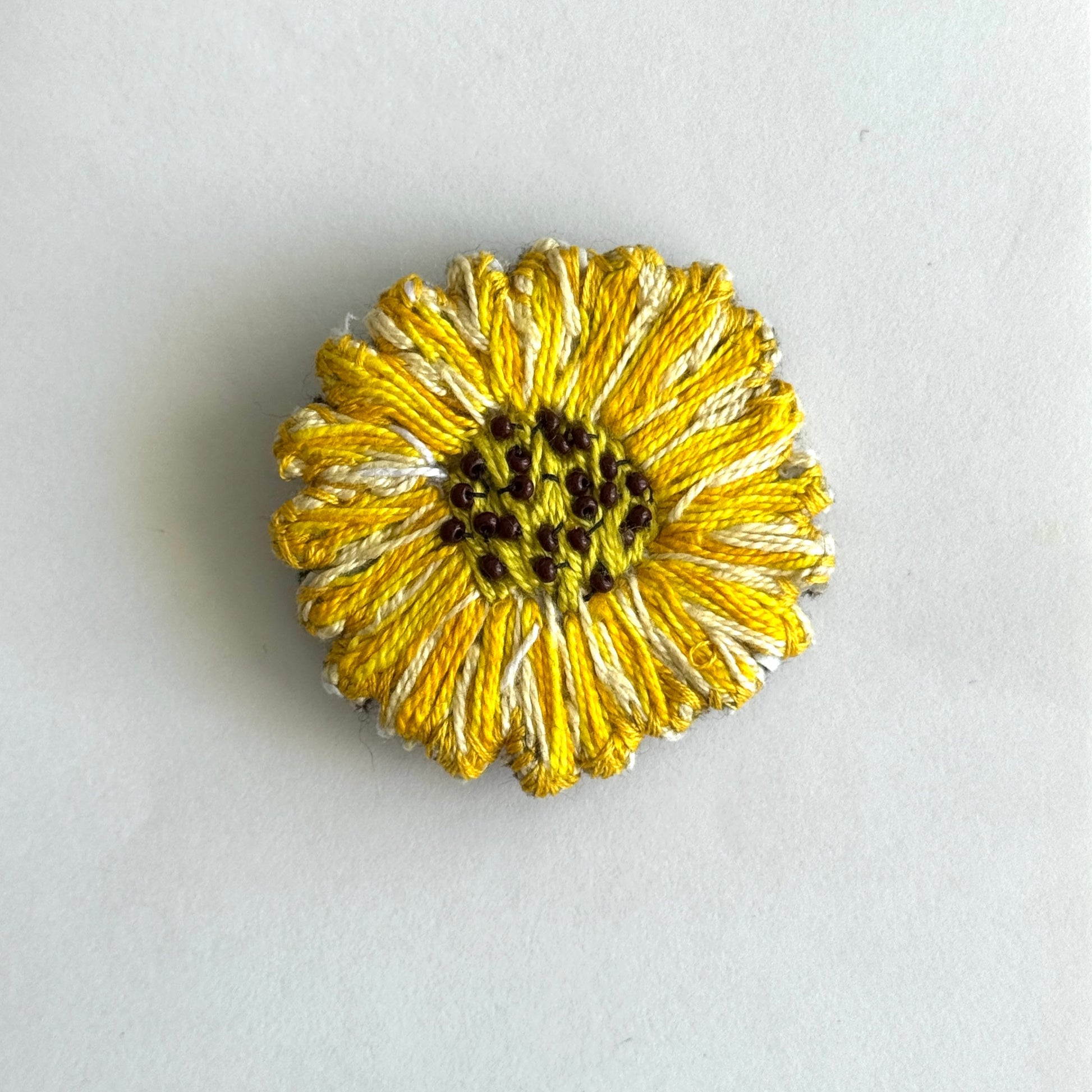 Gold flower-shaped brooch on a light gray background
