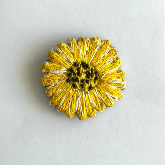 Gold flower-shaped brooch on a light gray background