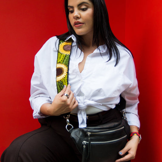 Woman holding a black bag with a colorful strap against a red background