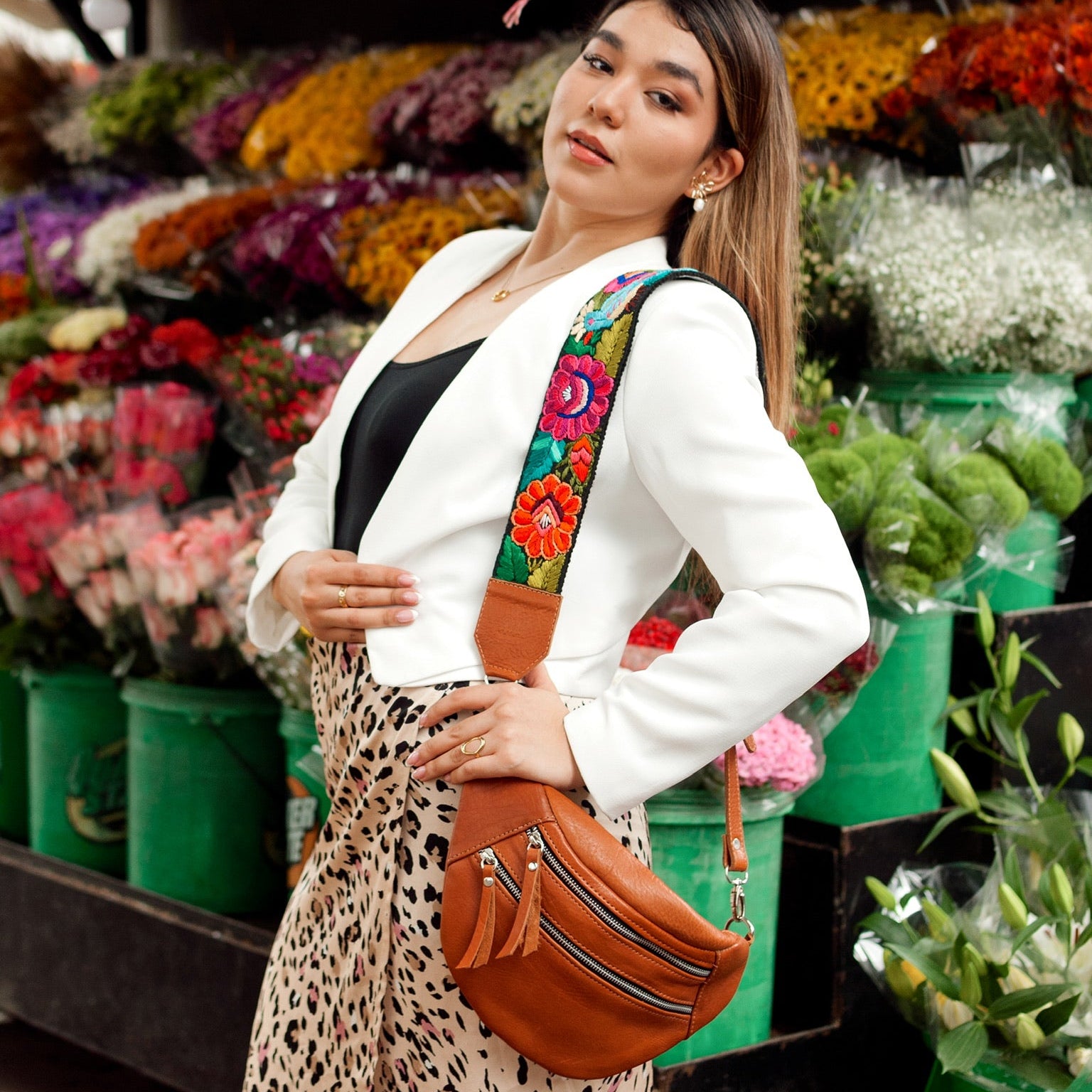 Woman with a colorful bag standing in front of a flower stand