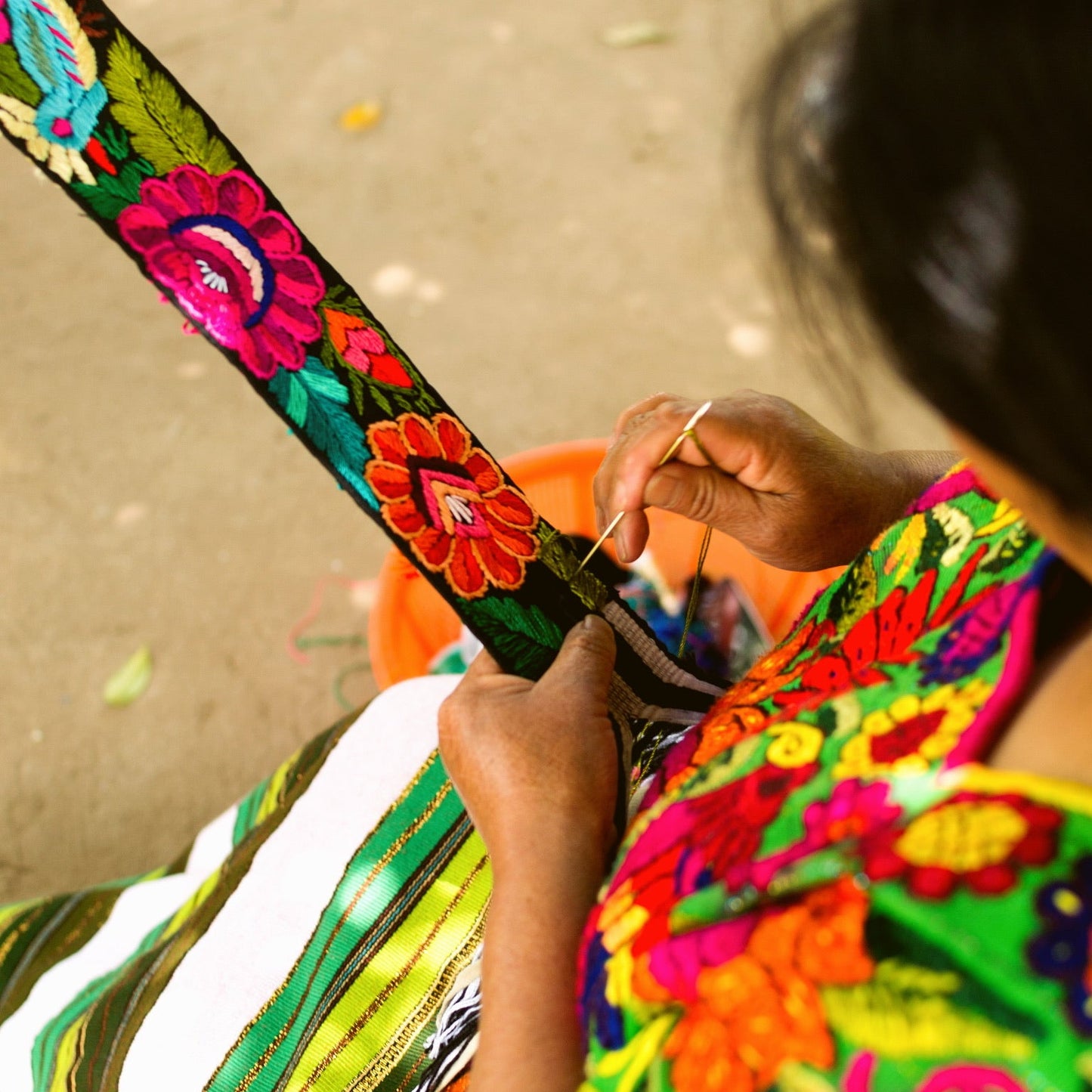 Person wearing a colorful embroidered garment with a floral strap.