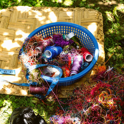 Basket with colorful yarn and spools on a grassy surface