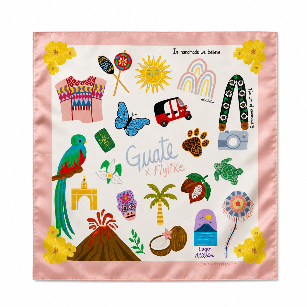 A square silk scarf featuring a colorful Guatemal-themed illustration on a light pink border. The design includes a blue-green parrot, yellow flowers, a rainbow, a red and white tuk-tuk, a blue butterfly, a green sea turtle, a palm tree, a volcano, a skull mask, and the text 'Guate X Flylike' and 'In handmade we believe'.