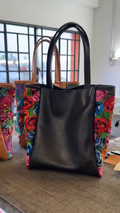 Black tote bag with colorful floral pattern on a wooden surface
