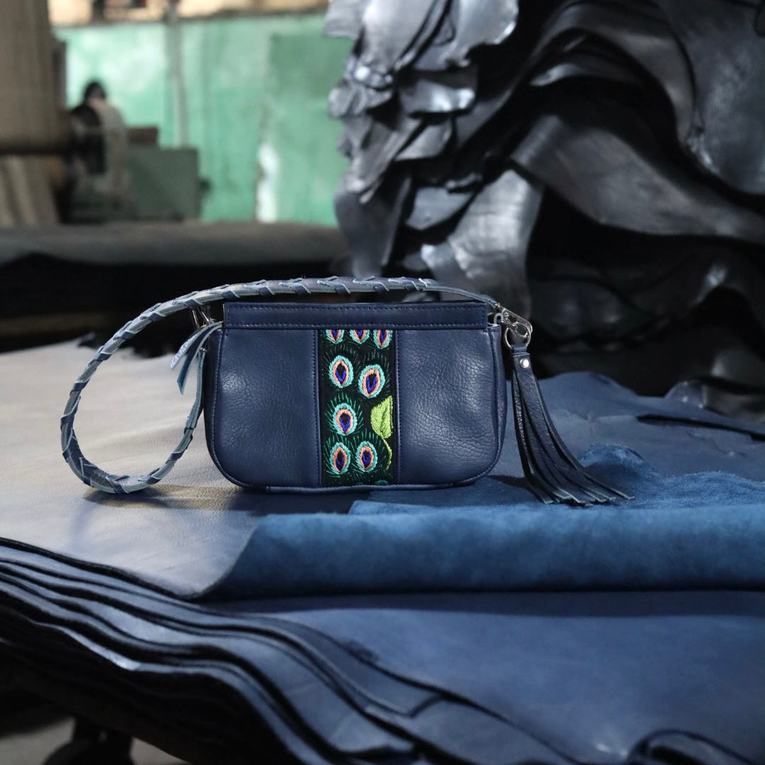 Blue handbag with decorative strap on a blue fabric surface