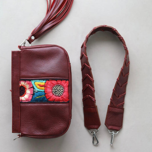 Brown leather wallet with floral embroidery and matching strap on a light gray background