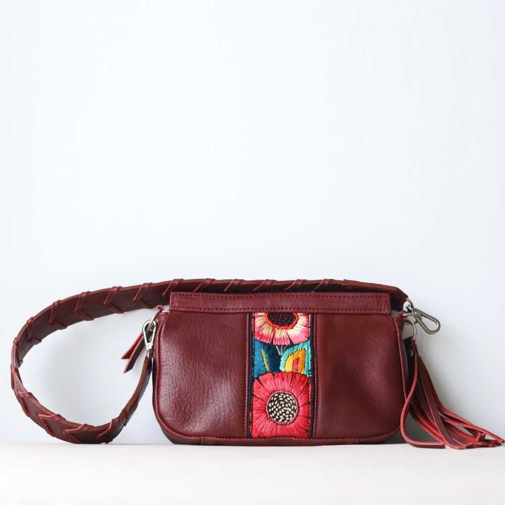Red leather handbag with floral embroidery on a white background