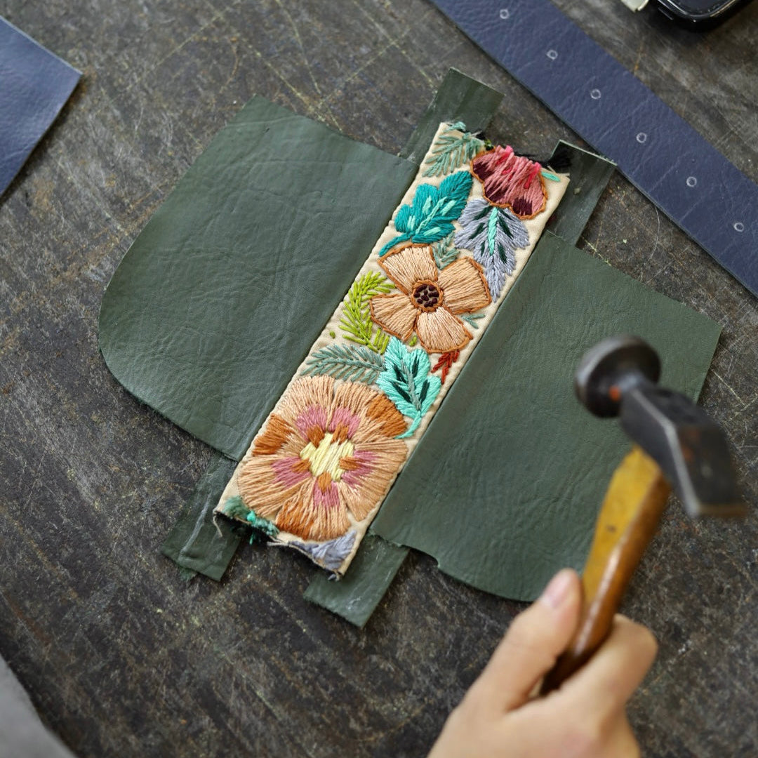 Handmade leather product with floral design on a wooden surface