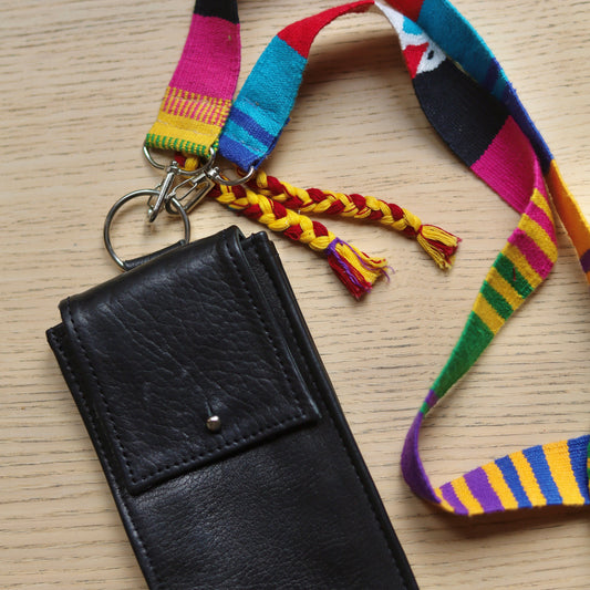 Black leather case with colorful strap on a wooden surface