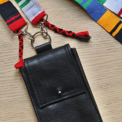 Black leather wallet with colorful braided strap on a wooden surface