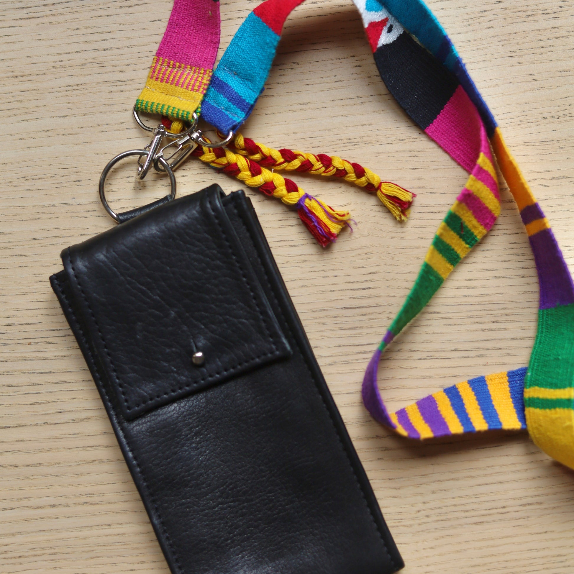 Black leather wallet with colorful strap on a wooden surface