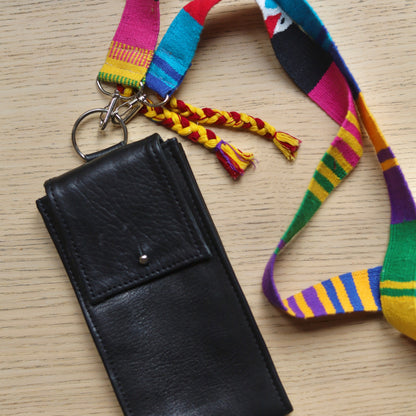 Black leather wallet with colorful strap on a wooden surface