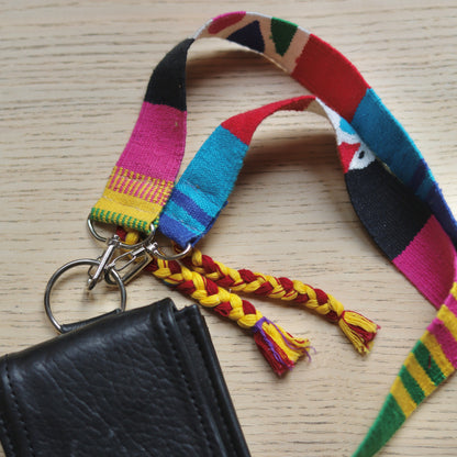 Black leather wallet with colorful striped lanyard on a wooden surface