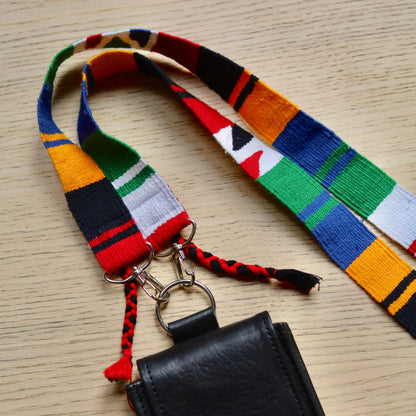 Colorful woven lanyard with a black pouch on a wooden surface