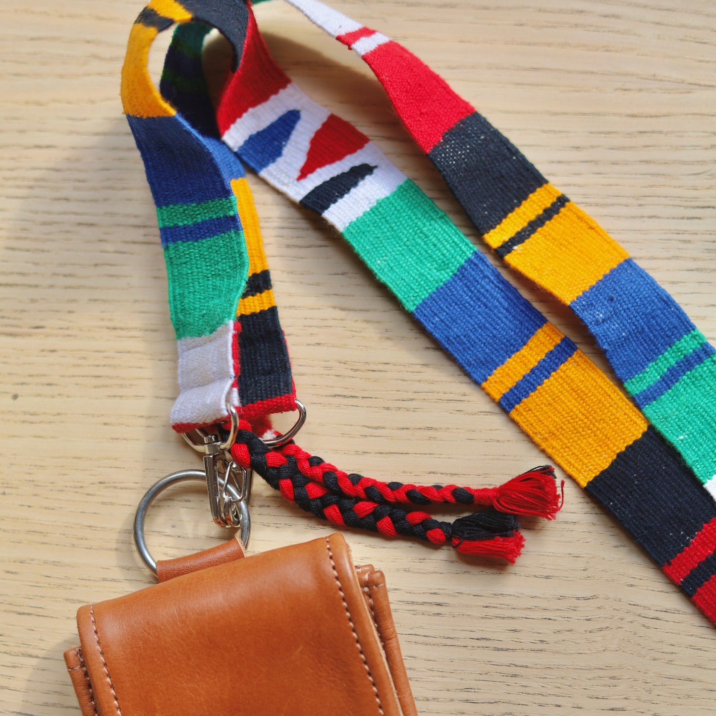 Brown leather phone case with colorful lanyard on a wooden surface