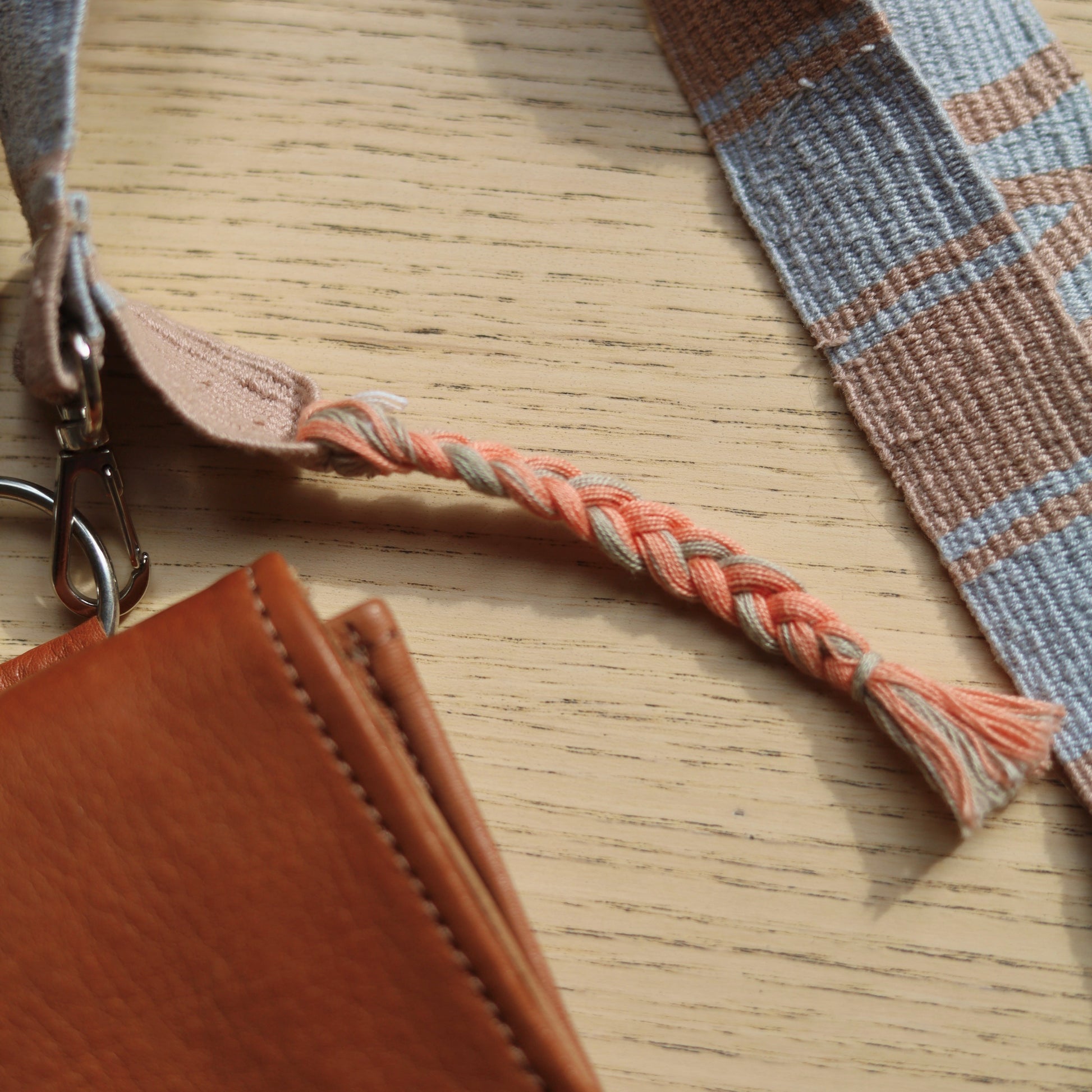 Brown leather pouch with plaid strap on a wooden surface